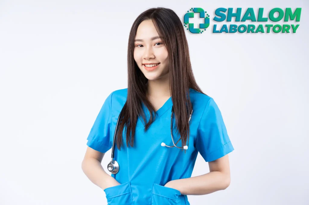 A standing nurse behind a white wall with her hands in her pocket.